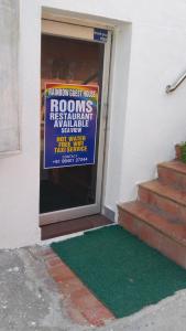 a sign on the door of a house with a green mat at Rainbow Guest House in Mahabalipuram