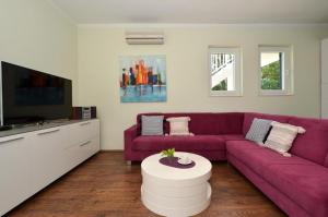 a living room with a purple couch and a tv at D&N Apartment in Kaštela