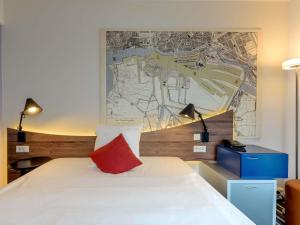 a bedroom with a white bed with a red pillow at Mercure Hotel Hamburg Mitte in Hamburg +121 photos