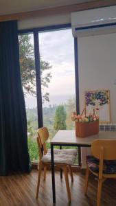 a dining room with a table and chairs and a large window at Sweet house in Kobuleti