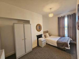 a bedroom with a bed and a cabinet and a window at Cheerful 4 bedroom close to Uclan, Preston City Center in Preston