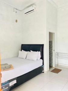 Una cama con sábanas blancas y almohadas en una habitación. en Bara Village Guest House Bira, en Bira