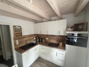 a kitchen with white cabinets and a sink at Lieblingsplatz in Wrixum