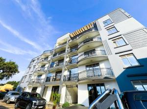 a white building with balconies and a car parked in front at Maja Apartments Kampala in Kampala