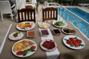 - une table avec des assiettes de nourriture à côté d'une piscine dans l'établissement Urcu Hotel, à Antalya
