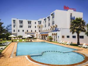 a hotel with a swimming pool in front of a building at Ibis El Jadida in El Jadida