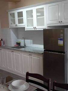 a kitchen with white cabinets and a black refrigerator at Urban Zen in Calamba