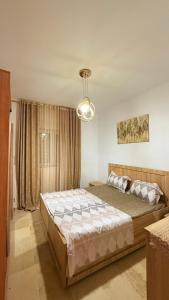 a bedroom with a large bed and a chandelier at Appartement S 1 résidence les Dunes sousse avec piscine in Sousse