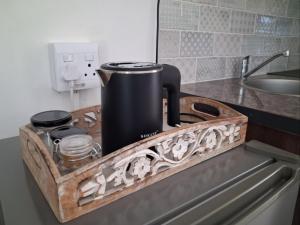 a black coffee pot on a wooden tray on a kitchen counter at Juliet Rose Luxury Guesthouse B&B in Bloemfontein +8 photos