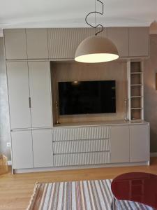 a living room with white cabinets and a flat screen tv at Mira apartman Oliva Residence in Petrovac na Moru