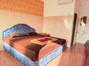 a bed with a blue headboard in a bedroom at Cempaka 2 Homestay in Legian