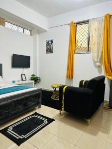 a bedroom with a bed and a couch and a tv at Charming Studio in Mombasa +3 photos
