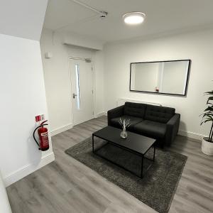 a living room with a black couch and a table at Charming 3 Bed Home Stay in Plumstead