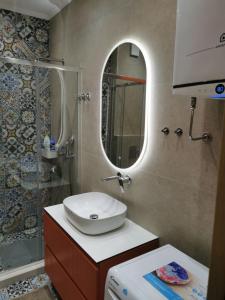a bathroom with a sink and a mirror and a shower at Mira apartman Oliva Residence in Petrovac na Moru