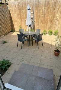 a patio with a table and chairs and an umbrella at Charming 3 Bed Home Stay in Plumstead