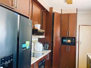 a kitchen with a stainless steel refrigerator and wooden cabinets at Inocova Fly in Kempton Park