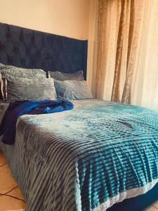 a bed with a blue blanket and pillows on it at Inocova Fly in Kempton Park +8 photos