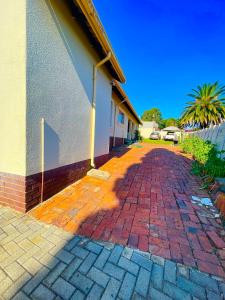 a brick driveway next to a building with a palm tree at Inocova Fly in Kempton Park