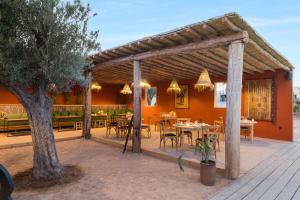 a wooden pergola with tables and chairs on a patio at Les Terrasses d'Agafay in El Karia