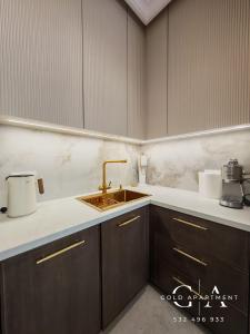 a kitchen with wooden cabinets and a sink at Gold Apartment E54 Let's Sea Baltic Park Gąski in Gąski