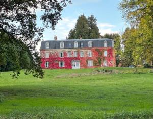een groot rood huis op een grasveld bij Château de Belleaucourt in Coulommes-la-Montagne