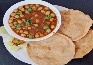 a plate with a bowl of chickpeas and pita bread at Capsule Hostel And PG Services in Gorakhpur +32 photos