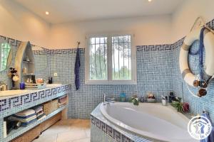 bagno piastrellato blu con vasca e finestra. di Le Loft de la garrigue a Cadolive