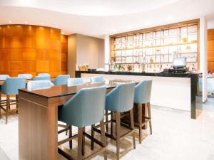 a restaurant with a bar with blue chairs at Sofitel London Gatwick in Horley