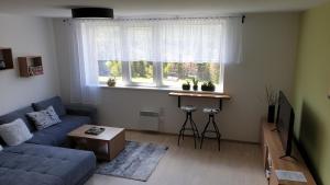 a living room with a blue couch and a window at Apartmán P7 Horní Mísečky in Horni Misecky