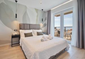 a bedroom with a large white bed with a balcony at Mediteran in Tučepi