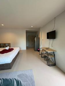 a bedroom with a bed and a table and a television at Cozy 1-Bedroom apartment in Ban Lum Fuang