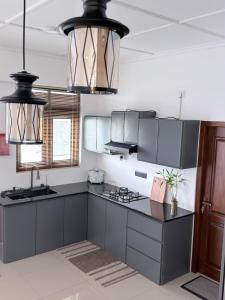 a kitchen with gray cabinets and black counters at The Altura Apartment in Mount Lavinia