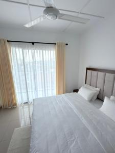 a bedroom with a large white bed with a ceiling fan at The Altura Apartment in Mount Lavinia