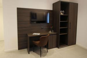 a desk with a television and a chair in a room at LA MUELE Affittacamere in Gemona del Friuli