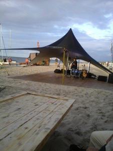 a black tent on the beach with a man sitting in it at Ferienwohnung Annelie in Zinnowitz +6 photos