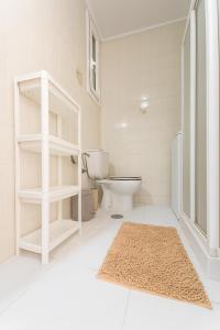 a white bathroom with a toilet and a rug at Beachfront Patalavaca in Patalavaca