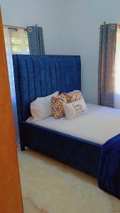a blue bed with two pillows on top of it at Zion Apartment Diani in Diani Beach