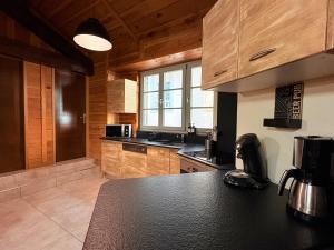 een keuken met houten kasten en een zwart aanrechtblad bij Le Douillet des Pyrénées, Luxury Chalet Home in Ax-les-Thermes +28 foto's