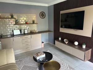 a living room with a tv and a couch and a table at UbuntuLifeStyleEstate-Premium Suite in Krugersdorp