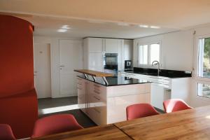 a kitchen with white cabinets and red chairs and a table at Ferienhaus Mostelrain in Sattel