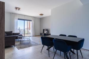 Pearl Beach Luxury Family Suite في ليماسول: غرفة معيشة مع طاولة وكراسي وأريكة