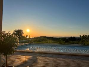 a sunset over a swimming pool with the sun setting at The best view in Marezige