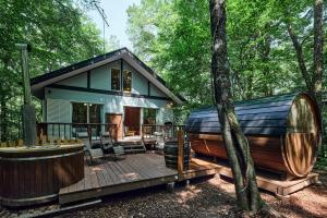 a house in the woods with a deck and a tub at Villa Noël Kitakaruizawa Jardin Forest Sauna Hideaway in Tsumagoi