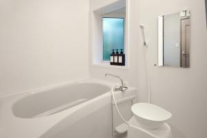 a white bathroom with a tub and a toilet at Villa Noël Kitakaruizawa Jardin Forest Sauna Hideaway in Tsumagoi +41 photos
