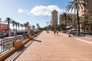 a sidewalk in a city with palm trees and buildings at Blanca Maris in Fuengirola