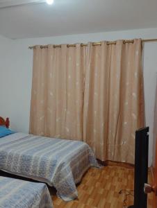 a bedroom with a bed and a curtain at Casa RRR in Caleta Cruz