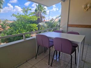 a balcony with a white table and purple chairs at Seru Coral Resort Appartement 188 in Willemstad