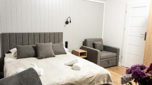 a bedroom with a large bed and a chair at Domki Dollar -Plaża Nowe Guty in Nowe Guty