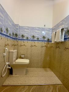 a bathroom with a toilet and palm trees on the wall at Abheena - Weligama in Weligama