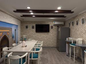 a dining room with a table and chairs and a tv at Hotel Taht in Tashkent